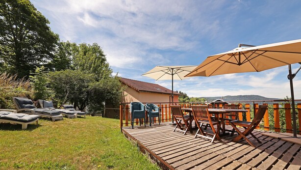 A deck with outdoor furniture, a table, and a large umbrella. - La Sabaudia Gîte in the Vosges – Up to 10 Guests (Gérardmer)