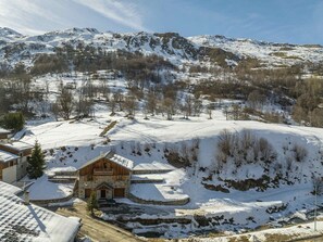 A rustic mountain lodge with a stone facade, a wooden balcony, and a snow-covered landscape. - Bright apartment with large terrace near slopes (Saint-Martin-de-Belleville)