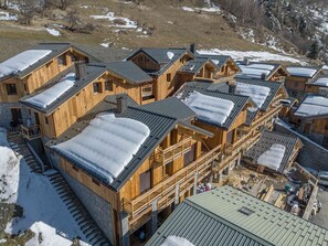 Een houten lodge met verschillende bungalows, elk voorzien van een balkon en een met sneeuw bedekte dak.
