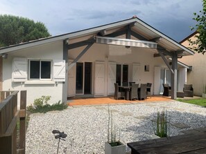 Uma casa moderna com um alpendre coberto, entrada com calçamento de brita e deck de madeira.