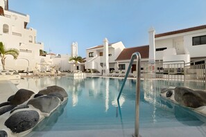 A swimming pool with lounge chairs and a lifeguard stand. - Holiday Apartment 'Penthause Luxe 501 Sea View Pool' with Sea View, Private Terrace and Wi-Fi (Costa Adeje)