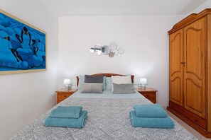 Un dormitorio con cama, dos mesitas de noche, un armario y una obra de arte en la pared.