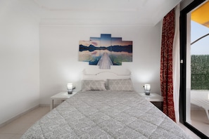 Une chambre à coucher avec un lit, une table de chevet, un tableau accroché au mur et une fenêtre avec des rideaux.