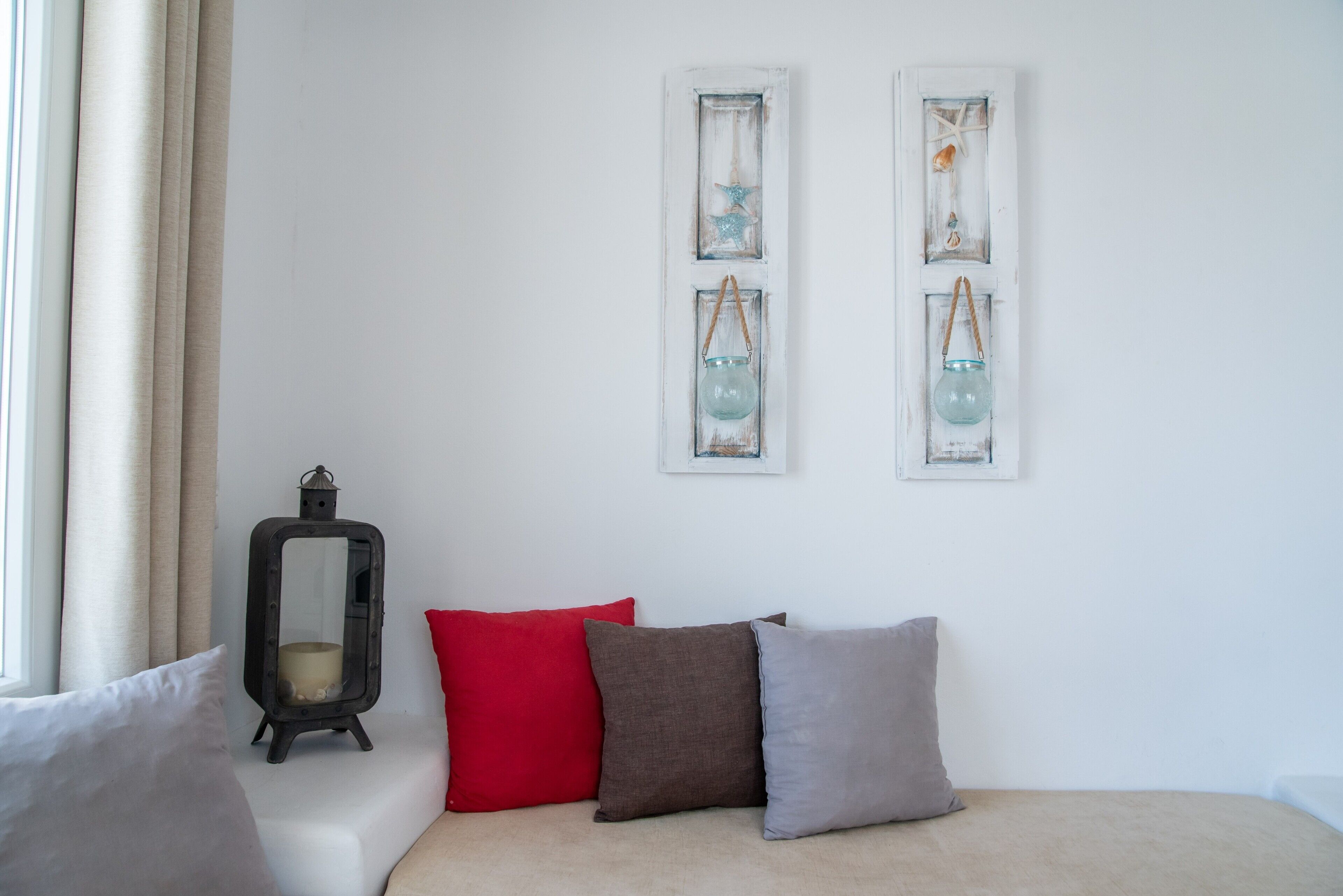 A room with a bed, a window with curtains, a wall-mounted lantern, and two wall decorations.