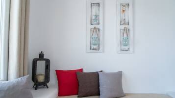 A room with a bed, a window with curtains, a wall-mounted lantern, and two wall decorations.