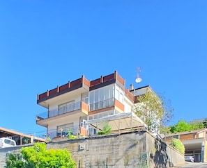En flervåningsbostadsbyggnad med balkonger, en satellitantenn och ett garage.