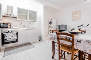 A modern kitchen with a microwave, oven, and built-in dishwasher. There is a dining table with chairs and a bowl on it.