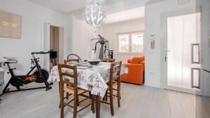 Un espace repas comprenant une table, des chaises, un luminaire au plafond, une porte et une fenêtre.