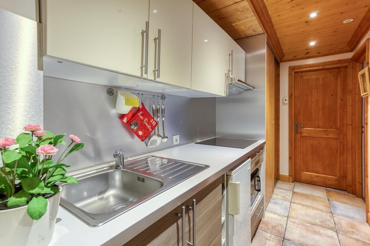 Een moderne keuken met roestvrijstalen apparatuur, een wit aanrecht en een houten plafond.