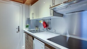 A modern kitchen with a stainless steel range hood, a built-in dishwasher, and a white countertop. - Appartement climatise au pied des cols avec wifi (La Bathie)