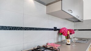 Een keuken met een gasfornuis, een gootsteen en een vaas met bloemen.