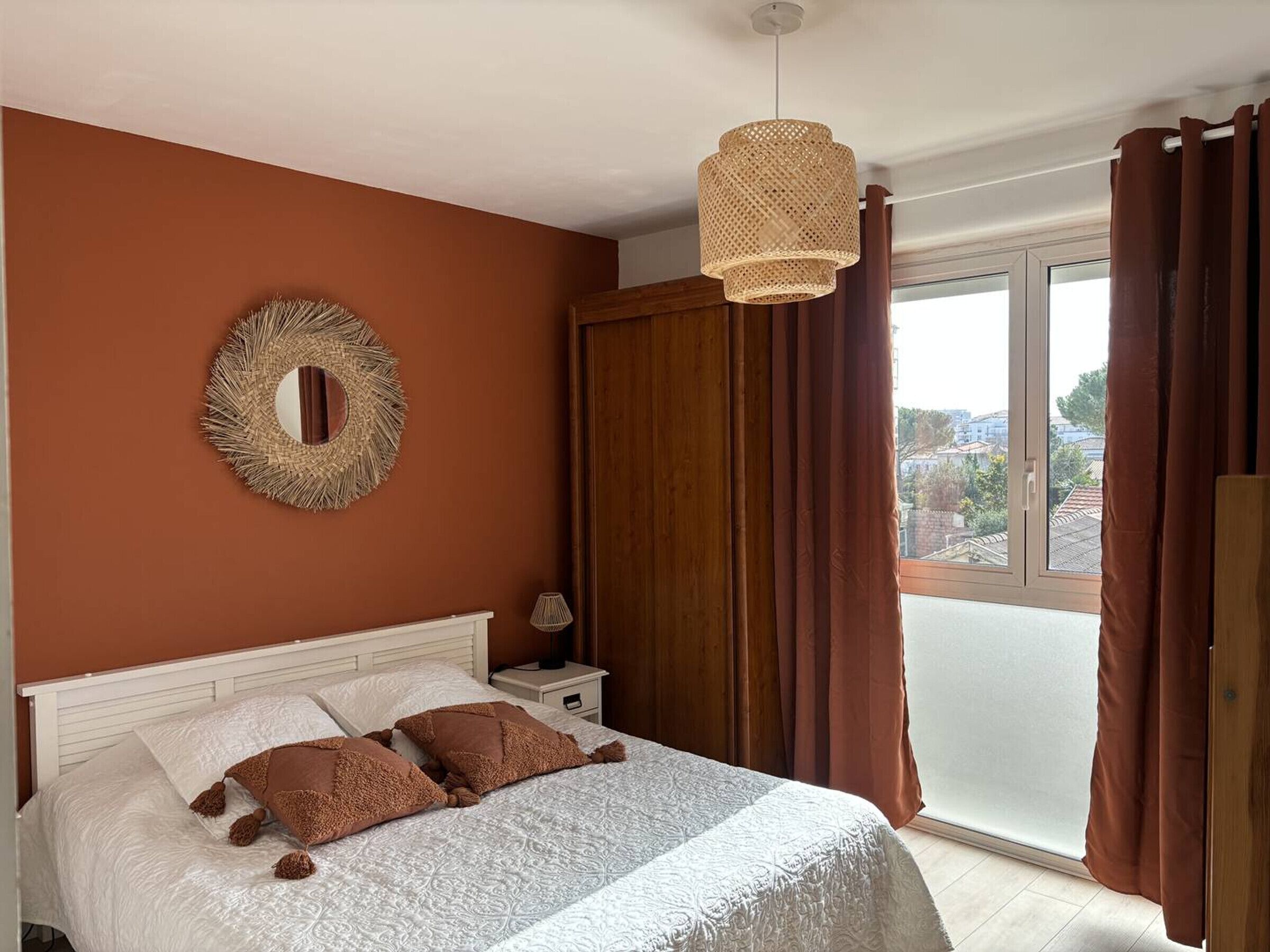 Una camera da letto con un letto, uno specchio rotondo, una lampada da comodino e vista all'esterno tramite una porta scorrevole.