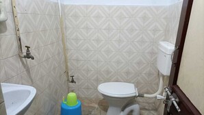 A small bathroom with a toilet, sink, and a blue cleaning tool. - Puri (Puri)