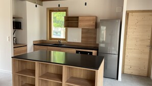 Una cocina moderna con una isla central, armarios de madera, un refrigerador de acero inoxidable y un ventanal que proporciona luz natural.
