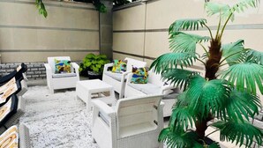 A patio area with white wicker furniture, including chairs and a table, and a large potted plant. - Hotel Diamond (Chisinau)