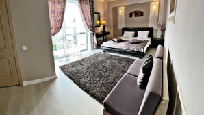 A modern bedroom with a large bed, a sofa, a rug, and a view of the outdoors. - Hotel Diamond (Chisinau)