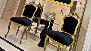 A room with a large mirror reflecting a famous painting, two ornate chairs, and a chandelier. - Hotel Diamond (Chisinau)