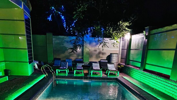 A swimming pool with a decorative tile pattern and green ambient lighting. - Hotel Diamond (Chisinau)