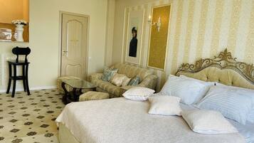 A hotel room with a bed, a sofa, a small table, and a chair.