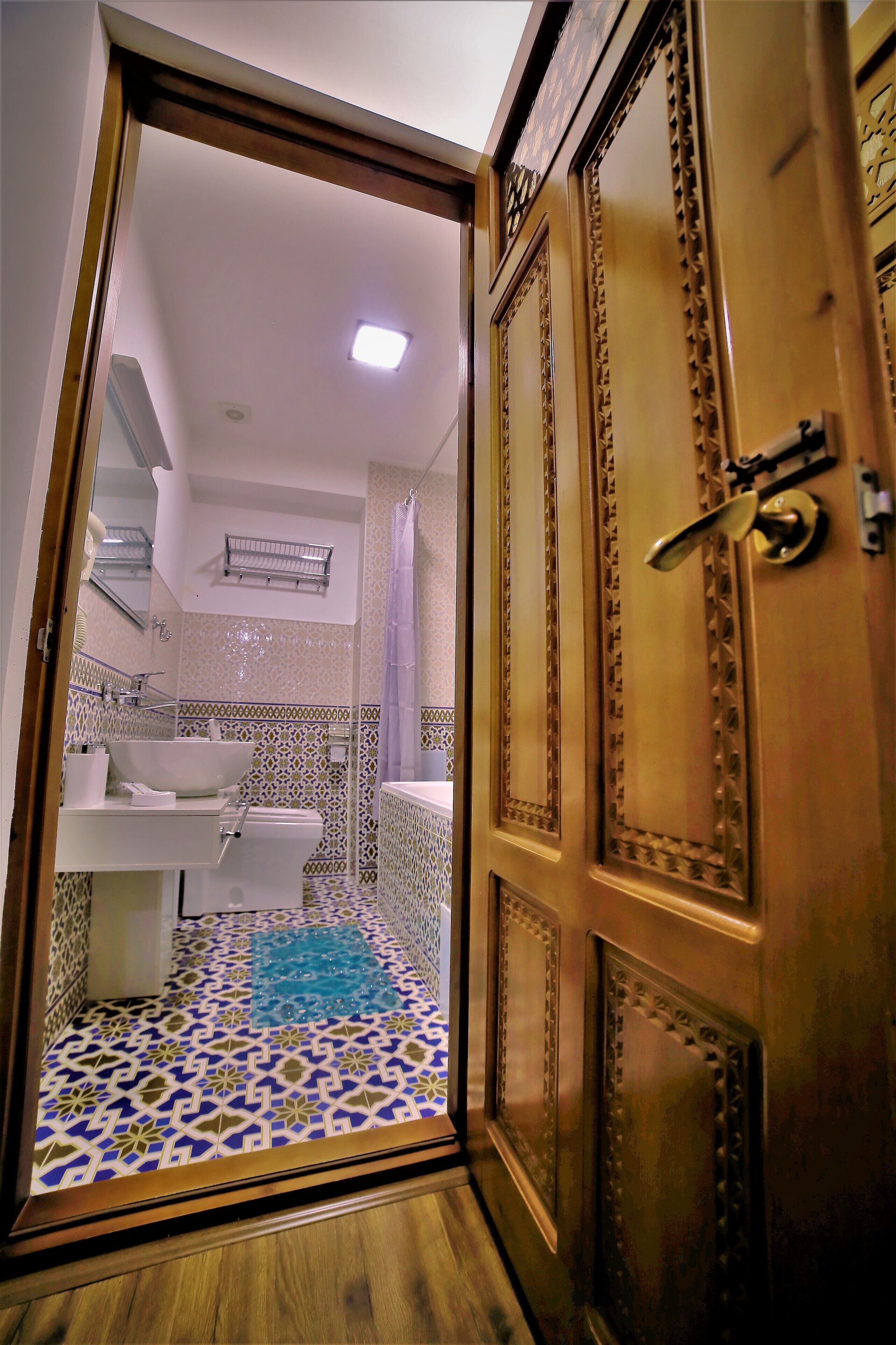 A bathroom with a patterned floor, a sink, and a shower area.