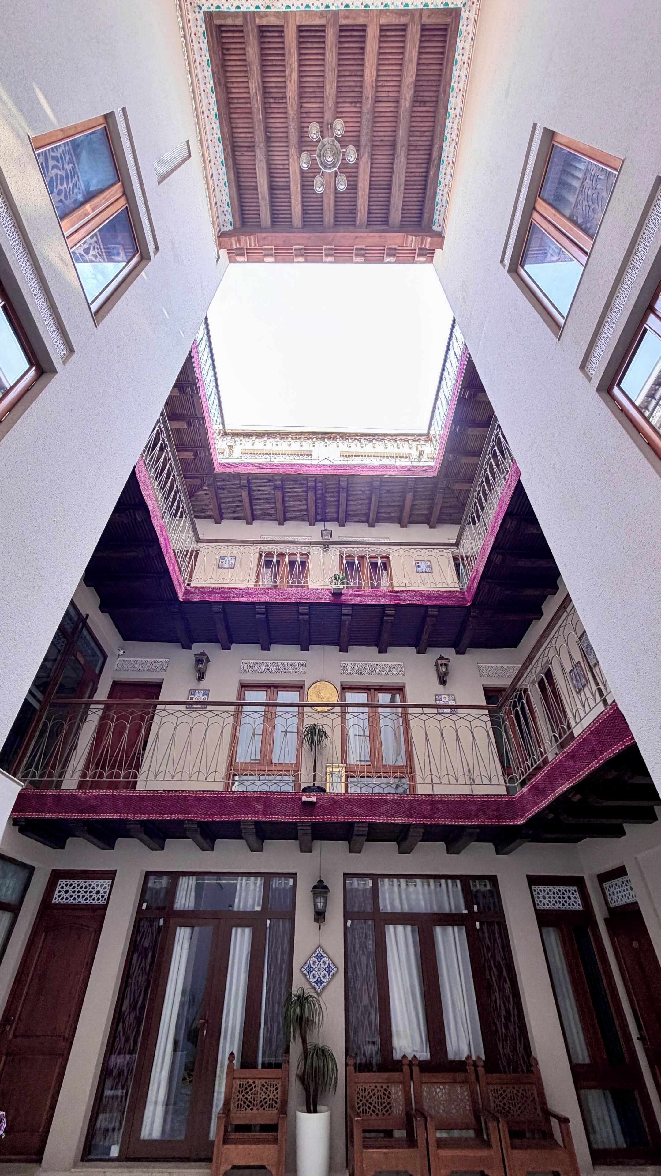 Un edificio a più piani con un cortile centrale, balconi con ringhiere elaborate e un lucernario.