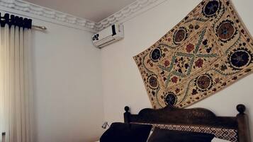 A neatly made bed with white linens and a patterned headboard.