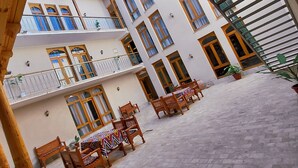 A multi-story building with balconies, wooden furniture, and potted plants. - Hotel Ansi Boutique W&S terrace (Bukhara)