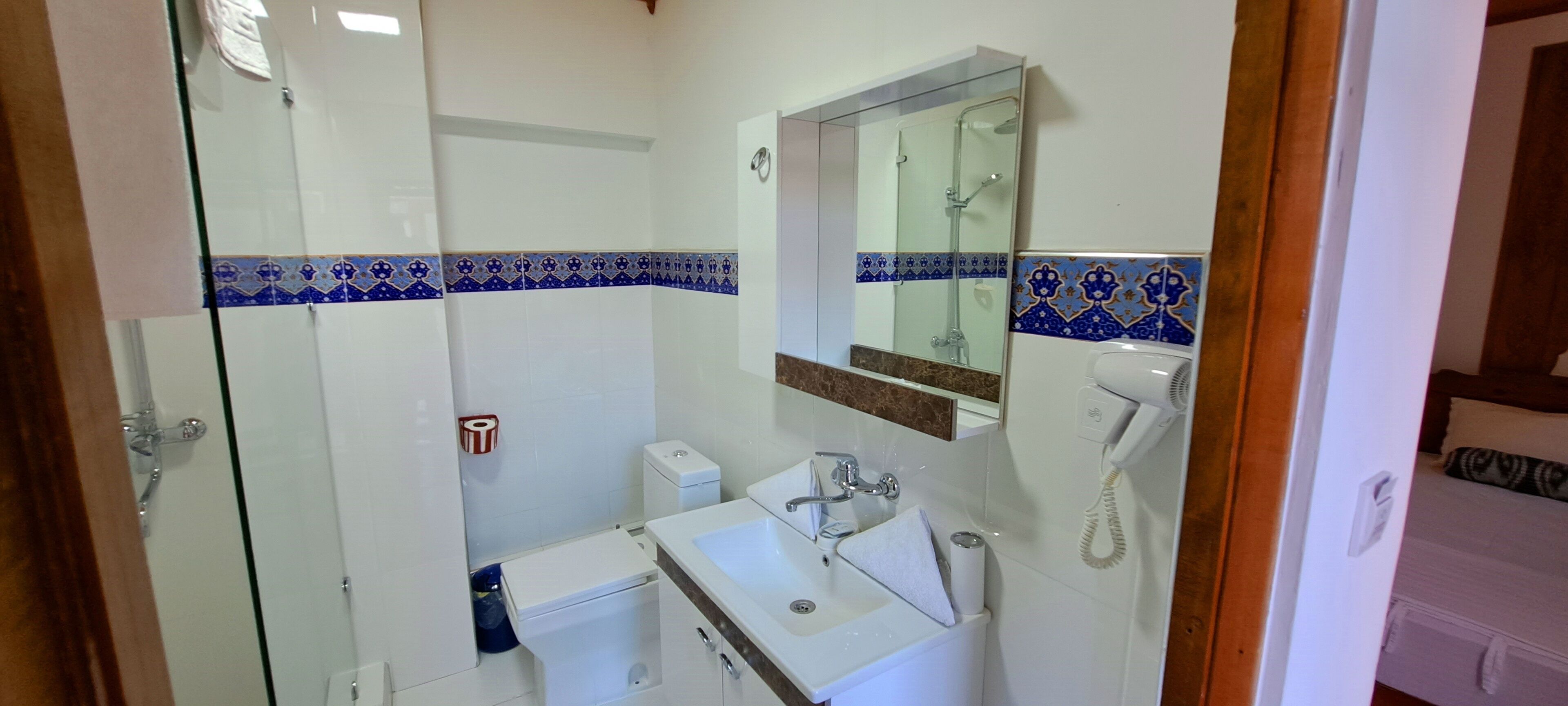 Een badkamer met een douchecabine van glas, een wastafel met spiegel en een toilet.
