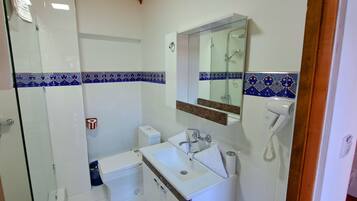 A bathroom with a glass shower enclosure, a sink with a mirror, and a toilet.