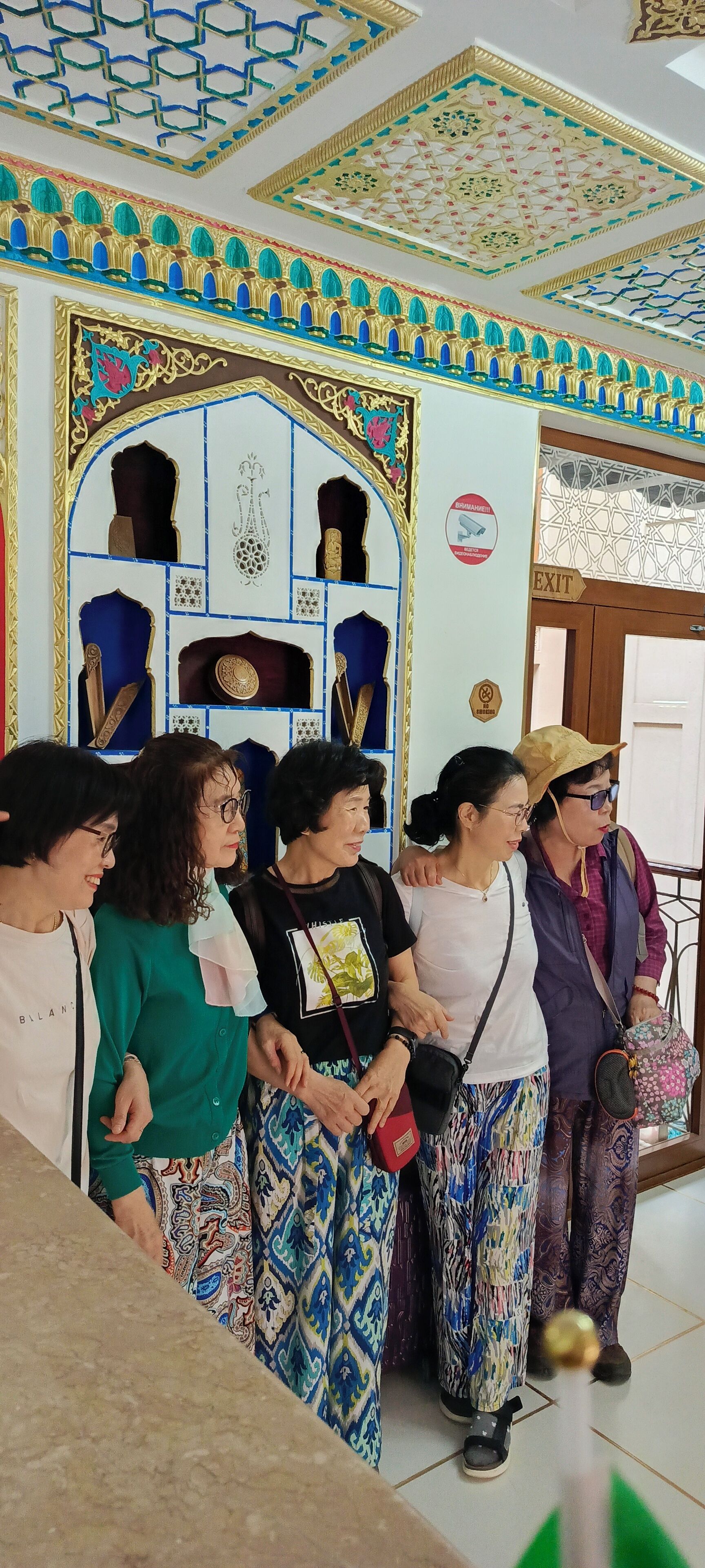 A group of people standing in a room with ornate ceiling designs and a decorative archway.