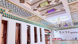 A hotel reception area with a sofa, reception desk, and a chandelier. - Hotel Ansi Boutique W&S terrace (Bukhara)