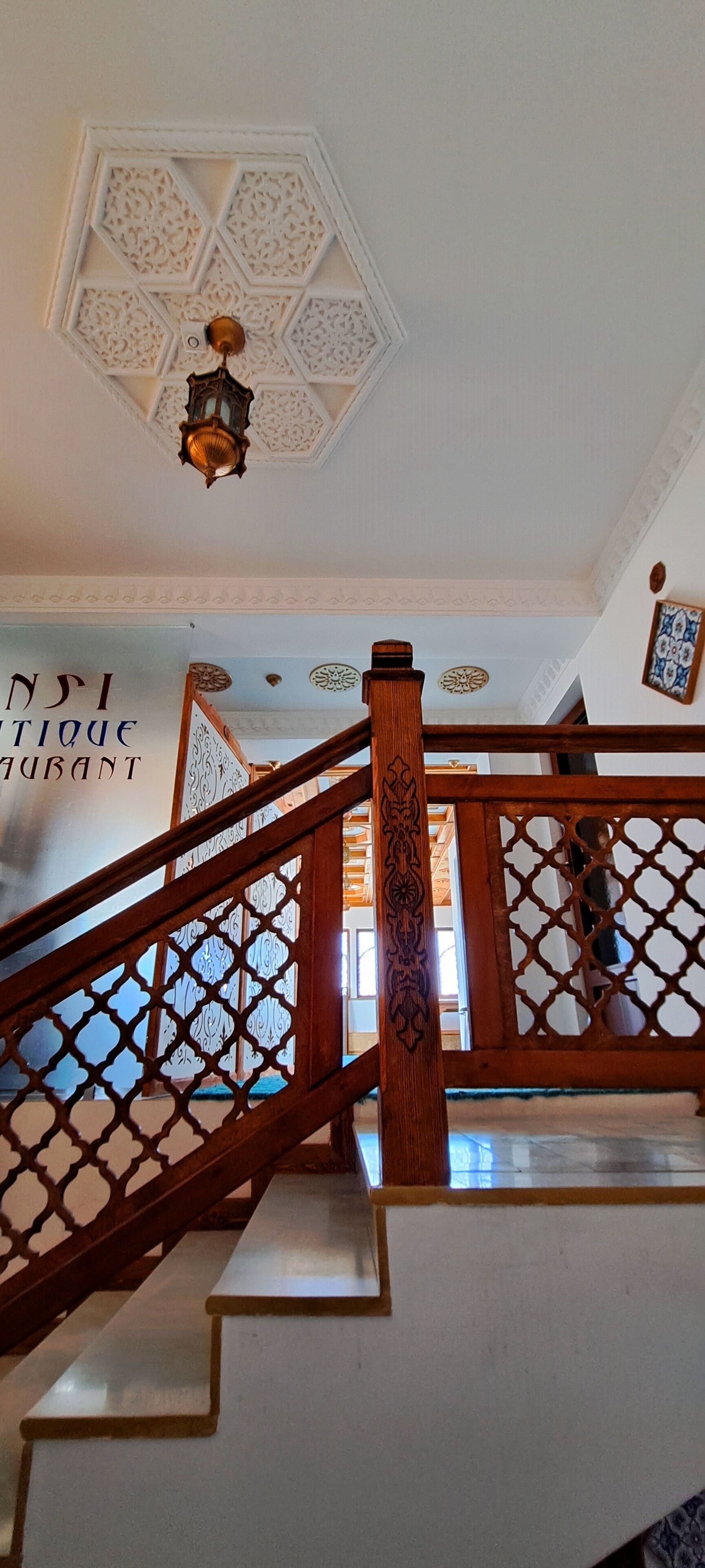 A staircase with intricate wooden railings and a decorative ceiling.
