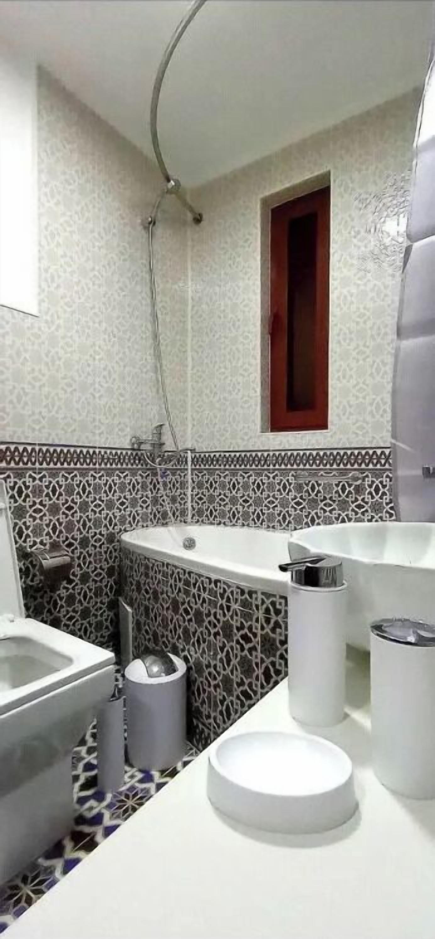 Baño con ducha, inodoro, lavabo y una ventana pequeña.