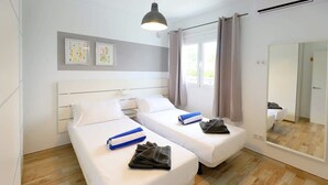 A hotel room with two single beds, a large mirror, and a wooden floor. - Villa Brisa Summary: (Playa Blanca)