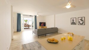 A modern living room with a sofa, a dining table with breakfast items, and a TV. - Villa Brisa Summary: (Playa Blanca)
