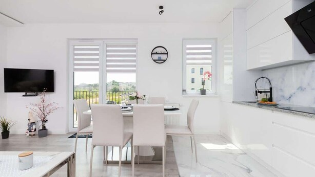 A modern kitchen with white cabinetry, a marble countertop, and a built-in oven.