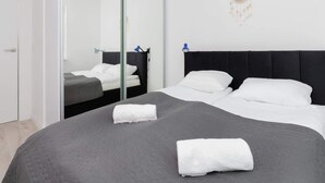 A modern hotel room with a large bed, a mirror, and a dreamcatcher on the wall.