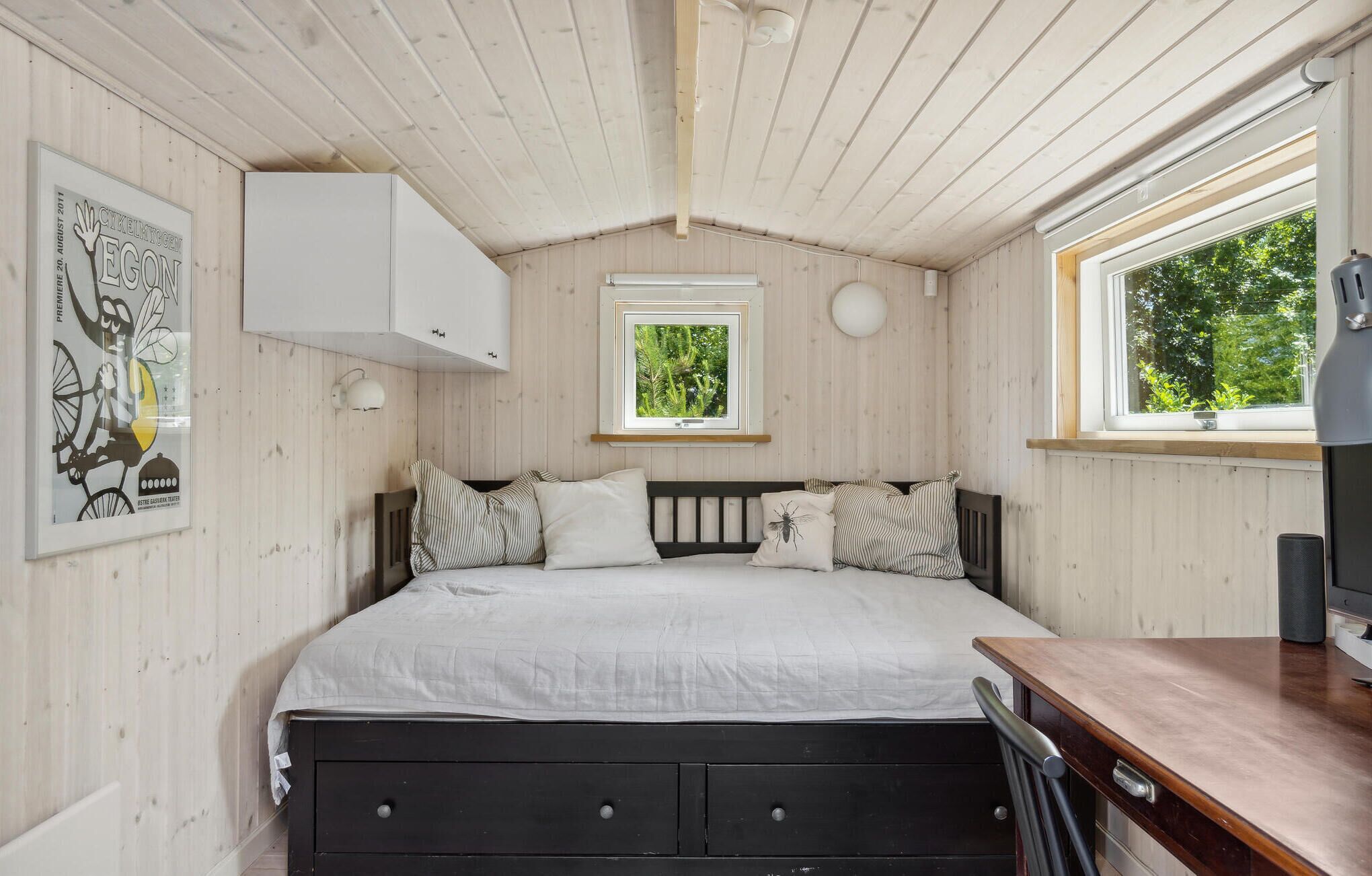 Un dormitorio con cama, escritorio, ventana y mueble empotrado.