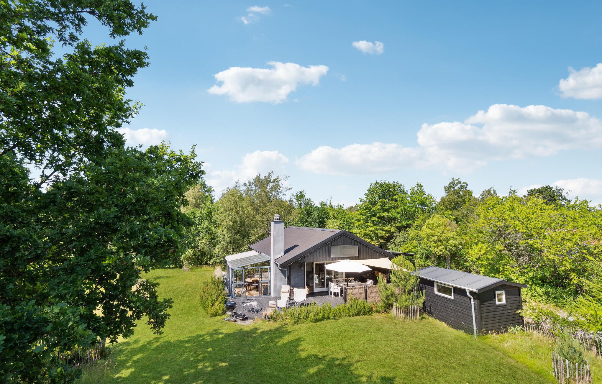 A house with a covered patio, a small shed, and a lawn.