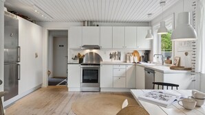 Ett modernt kök med vita skåp, rostfria vitvaror och en köksö i mitten.