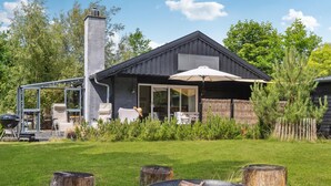 Ett modernt hus med en stor uteplats, utomhusmöbler och en grillplats.
