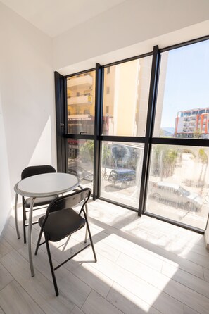 A room with a large window, a round table, and two chairs. - Hotel Beler (Vlorë)