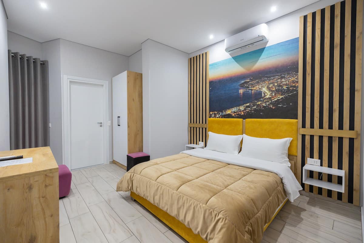 Une chambre moderne avec un grand lit, un bureau et une vue sur la ville.