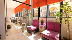 A modern interior with a seating area, a reception desk, and a view of the outside. - Hotel Beler (Vlorë)