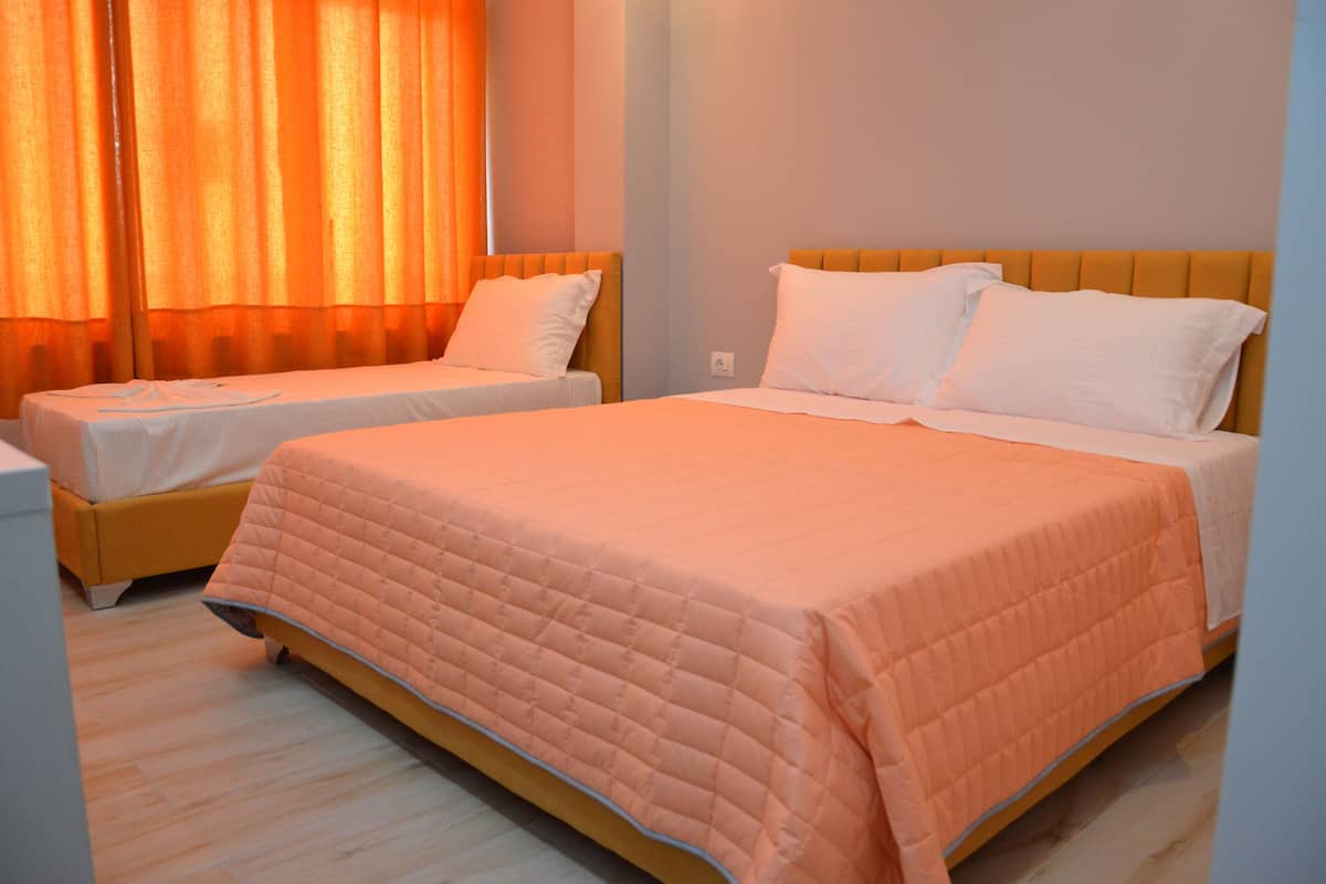 Une chambre d’hôtel avec deux lits, chacun doté d’une tête de lit et d’oreillers, ainsi qu’une grande fenêtre avec des rideaux.