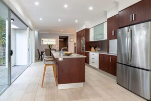 A modern kitchen with a central island, stainless steel appliances, and a sliding glass door leading to an outdoor area.
