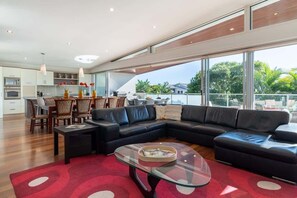Una sala moderna con un sofá modular, una mesa de centro de vidrio y un comedor con sillas de mimbre.