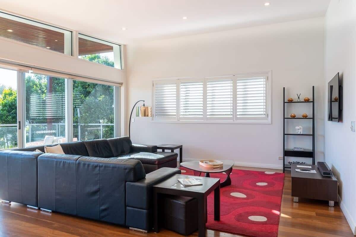 A modern living room with a sectional sofa, a coffee table, and a red patterned rug.