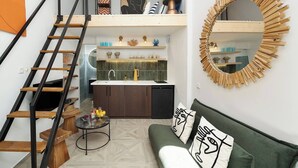 Een modern loft appartement met een vide, een keuken met een geïntegreerd kookeiland en een ronde spiegel met houten lijst.