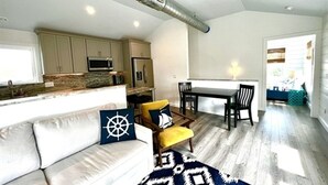 A modern kitchen with built-in appliances, a dining area with a table and chairs, and a cozy seating area with a sofa and cushions. - Cozy home sleeps 4 & just a few steps to the beach & Linens Included! (Edisto Island)
